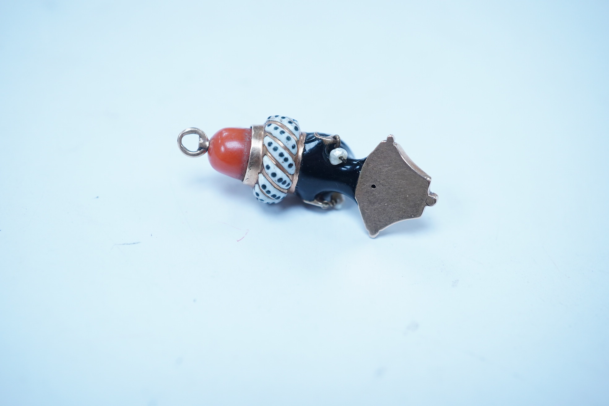 A yellow metal, enamel gem and coral bead set blackamoor bust charm, 32mm. Condition - poor